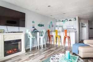 een woonkamer met open haard en kleurrijke barkrukken bij Coastal Serenity 108 Beachfront Condo Near Downtown in Fivemile Corner