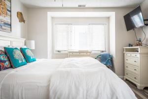 een witte slaapkamer met een wit bed en een raam bij Coastal Serenity 108 Beachfront Condo Near Downtown in Fivemile Corner +32 foto's
