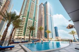 a swimming pool with palm trees and tall buildings at StayMada - Torch Tower Elegant Marina Retreat in Dubai