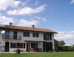 a large white house with a balcony and a dog at B&B Cascina Dei Levrieri in Capriglio