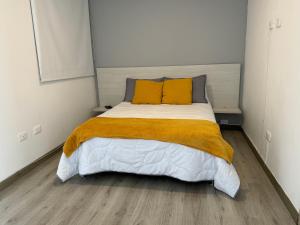 a bedroom with a large bed with two yellow pillows at Exclusivo Apartamento en Panoramika Laureles Rodeado de Naturaleza in Armenia