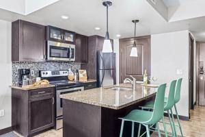 eine Küche mit Holzschränken und einer Theke mit grünen Stühlen in der Unterkunft Rockies Getaway 2BR with Patio Hot Tub and Gym in Dead Man's Flats + 28 Fotos