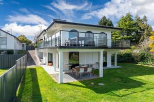 Cette maison blanche dispose d'un balcon et d'une cour. dans l'établissement Ultimate Lakefront Getaway, à Waitahanui