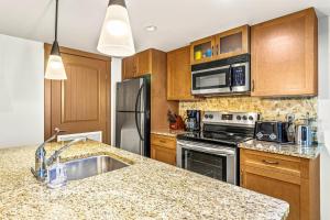 a kitchen with wooden cabinets and a granite counter top at Contemporary 2BR with hot tub and Mountain Views in Dead Man's Flats +18 photos