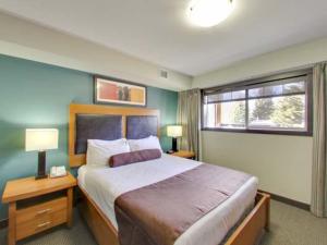 a bedroom with a large bed and a window at Cozy Condo With Hot Tub Gym and Underground Parking in Dead Man's Flats