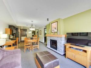 a living room with a fireplace and a dining room at Cozy Condo With Hot Tub Gym and Underground Parking in Dead Man's Flats