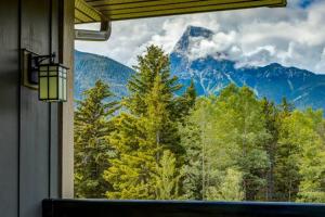 a window in a room with a view of a mountain at Lovely 3BR condo with Hot Tub at the Edge of Canmore in Dead Man's Flats
