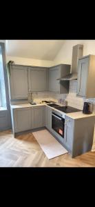 een keuken met witte kasten en een kookplaat oven bij Kirkgate 2 bed - Coorie Doon Stays in Irvine