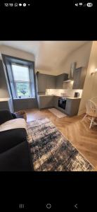 een woonkamer met een bank en een groot raam bij Kirkgate 2 bed - Coorie Doon Stays in Irvine