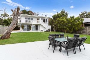 een terras met een tafel en stoelen voor een huis bij Whispers of Sunset in Dromana