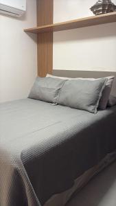 a bedroom with a bed with a gray blanket and pillows at Flat Moderno a 100m da Praia do Bessa in João Pessoa +8 photos