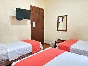 a room with two beds and a flat screen tv at Xpress Inn in Veracruz