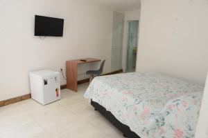 サルバドールにあるPousada gran souzaのベッドと机とテレビのある寝室