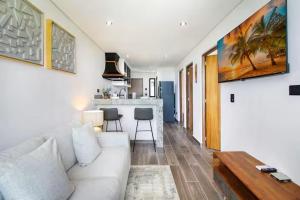 a living room with a white couch and a kitchen at Cozy Playa Escape Pool, Beach & 5th Avenue in Playa del Carmen +16 photos