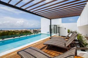 a deck with chairs and a swimming pool on a building at Cozy Playa Escape Pool, Beach & 5th Avenue in Playa del Carmen