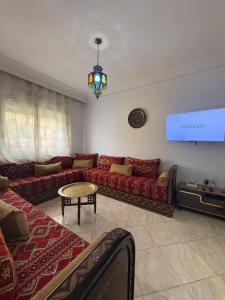 a living room with red couches and a television at Résidence jawharat mogador in Essaouira