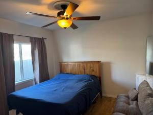 Schlafzimmer mit einem blauen Bett und einem Deckenventilator in der Unterkunft The Ardmore Home Share in Los Angeles