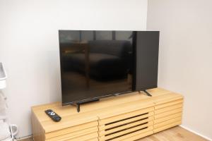 a flat screen tv sitting on top of a wooden entertainment center at oyadoya gifu kano 岐阜駅徒歩12分 名古屋駅35分 大人数貸切 最大8名 駐車場有り in Gifu