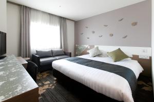 a hotel room with a bed and a chair at Toyama Excel Hotel Tokyu in Toyama