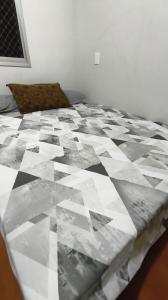 a bed with a black and white quilt on it at Cobertura Duplex super confortável melhor localização BH in Belo Horizonte +3 photos