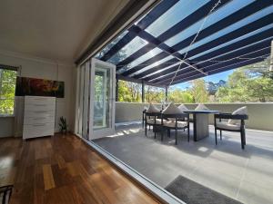 a dining room with a table and chairs and a large window at Tranquil Leura 3BDR Unit 3 Minutes to Shops in Leura