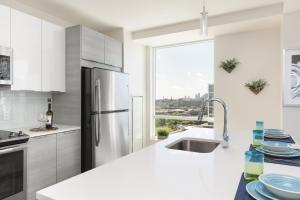 a white kitchen with a refrigerator and a sink at Luxury Apartments by Hyatus at Boston Assembly Row in Somerville