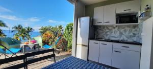 a kitchen with white cabinets and a balcony with a view at Turquoise studio remarquable vue mer in Le Diamant