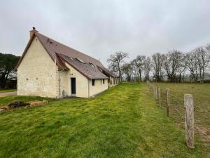 a building in a field next to a fence at Gîte de charme près du Mans, tout équipé avec espace extérieur, garage, et confort moderne - FR-1-410-385 in La Bosse
