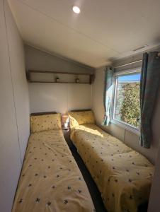 two beds in a small room with a window at Pet friendly holiday home located at Littlesea Holiday Park, In Weymouth, Dorset in Wyke Regis +16 photos