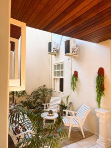 two chairs and a table on a patio with plants at Pousada da Orla in Itacaré