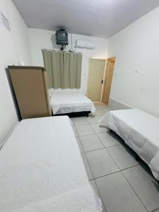 a bedroom with two beds and a tv on the wall at Hotel Pousada Aquarius SOB NOVA DIREÇÃO in Aruanã