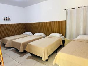 a group of four beds in a room at Hotel Pousada Aquarius SOB NOVA DIREÇÃO in Aruanã