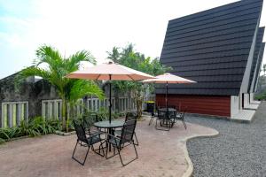 eine Terrasse mit Tischen, Stühlen und Sonnenschirmen in der Unterkunft RedDoorz @ myRoom UMY in Yogyakarta