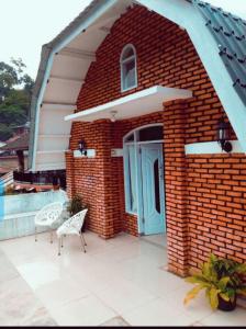 ブキットラワンにあるTiga dara guest house jungle trekkingの青いドアと椅子2脚が備わるレンガ造りの建物