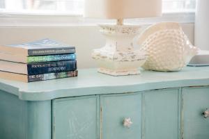 a blue cabinet with a lamp and books on it at Cozy Coastal Cottages of Dunedin in Dunedin