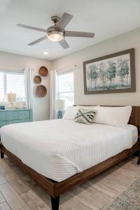 a bedroom with a large bed with a ceiling fan at Cozy Coastal Cottages of Dunedin in Dunedin