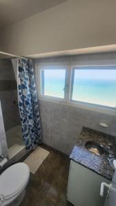 een badkamer met een toilet, een wastafel en twee ramen bij Miramar Vista al Mar in Miramar