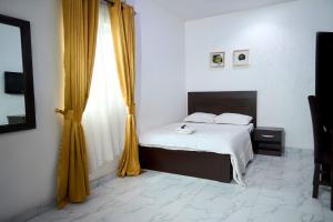 um quarto com uma cama e uma janela com cortinas amarelas em Anuoluwapo Taiwo Hotels em Lagos