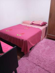 a bedroom with two beds with pink sheets and a pink rug at Quarto para cop 30 in Ananindeua