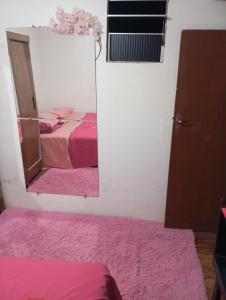 a bedroom with a mirror and a bed with pink sheets at Quarto para cop 30 in Ananindeua