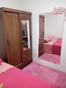 a bedroom with a mirror and a bed with pink sheets at Quarto para cop 30 in Ananindeua