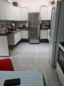 a kitchen with white cabinets and a stainless steel refrigerator at Quarto próximo Consulado Americano e metrô Borba Gato in São Paulo +4 photos