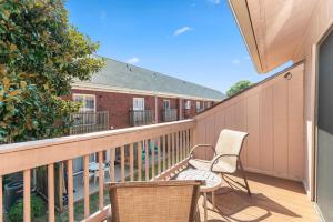 a balcony with two chairs and a fence at 3 min walk to beach, 2 person hot tub, 1 mile drive to airport in Myrtle Beach