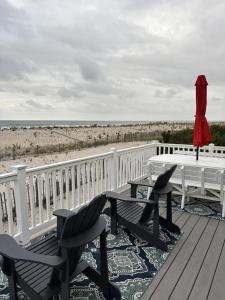 a deck with chairs and a table and a bench and the beach at Holgate Ocean Front Duplex 2Nd Fl 14018 in Holgate