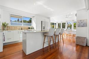 een open keuken met witte kasten en barkrukken bij The Whitewater House, Peregian Beach in Peregian Beach