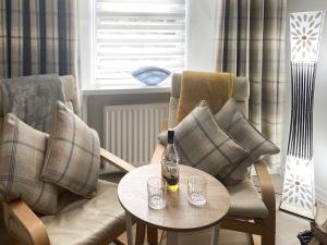 a room with two chairs and a table with a bottle on it at Holly Cottage in Palnackie