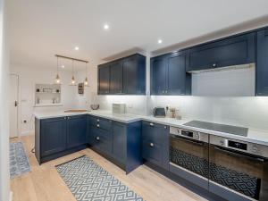 a kitchen with blue cabinets and white counter tops at Warrington House-Uk48465 in Thornton Dale