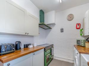 eine Küche mit weißen Schränken und einem Herd mit Backofen in der Unterkunft Chapel Bay Cottage in Angle + 20 Fotos