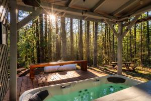 Un jacuzzi en una terraza de madera con un banco. en Stay Portland - Relaxing River Retreat, en Rhododendron