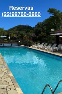 a swimming pool with blue water and white chairs at Estação Serramar in Lumiar